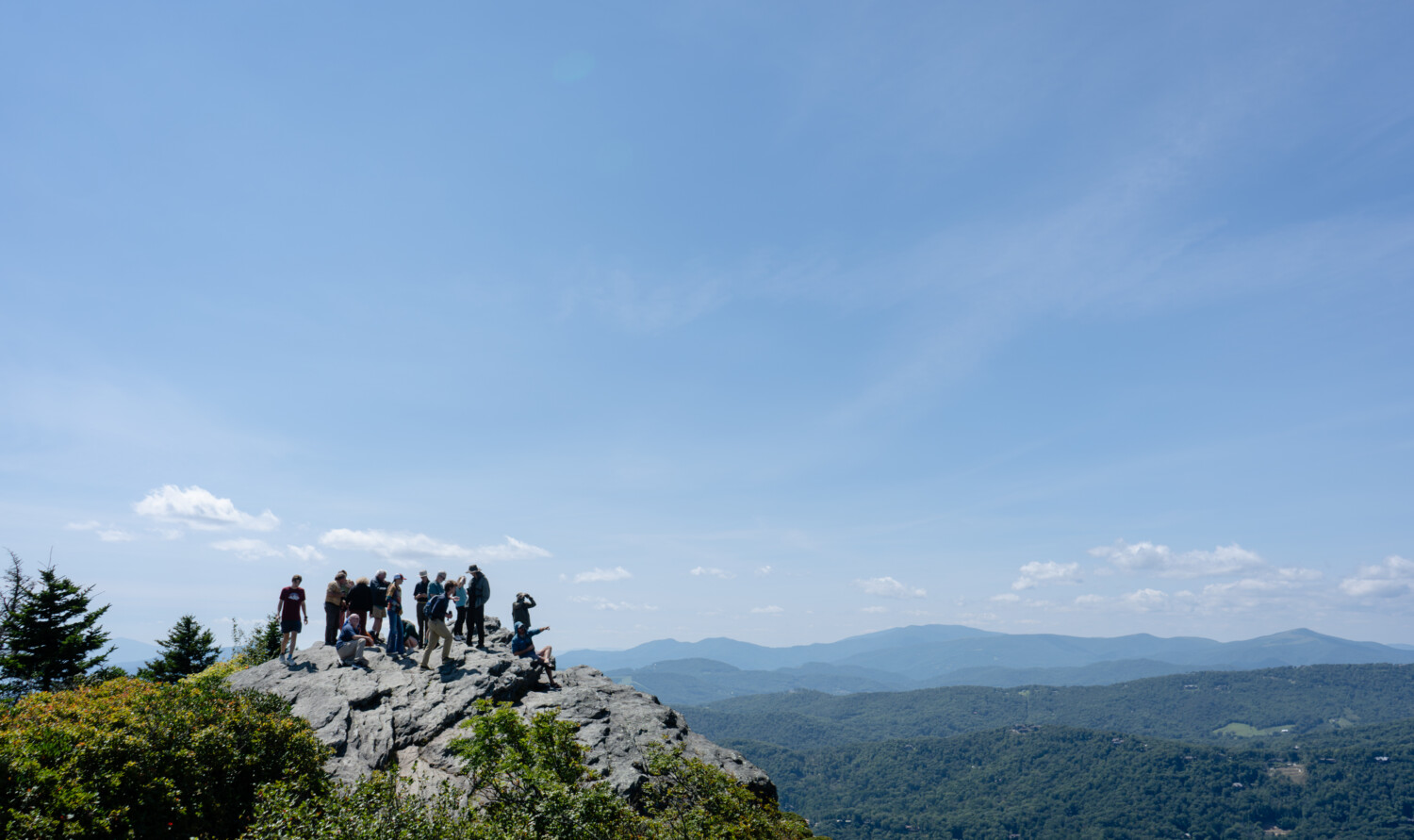 A group of people in the distance on a mountain peak on sunny day